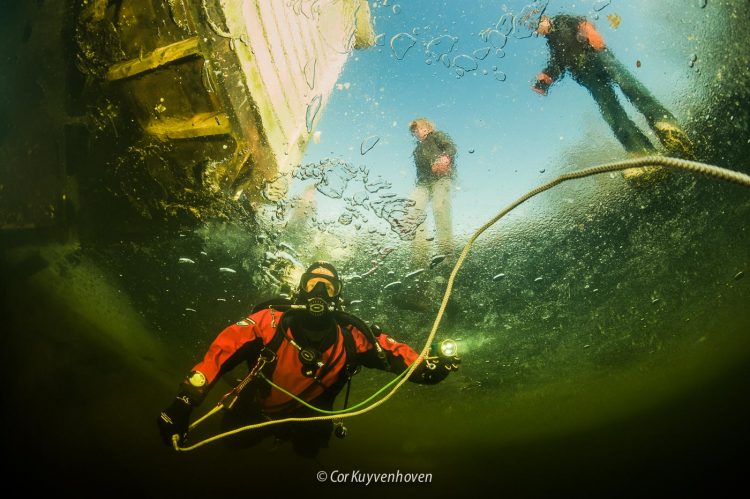 Duiker onder het ijs met wandelaars