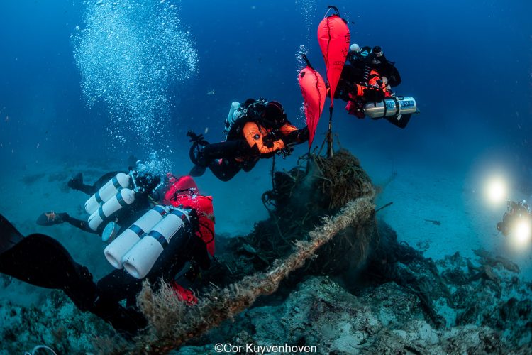 Duikers van Ghost diving liften een net van een Ghost farm