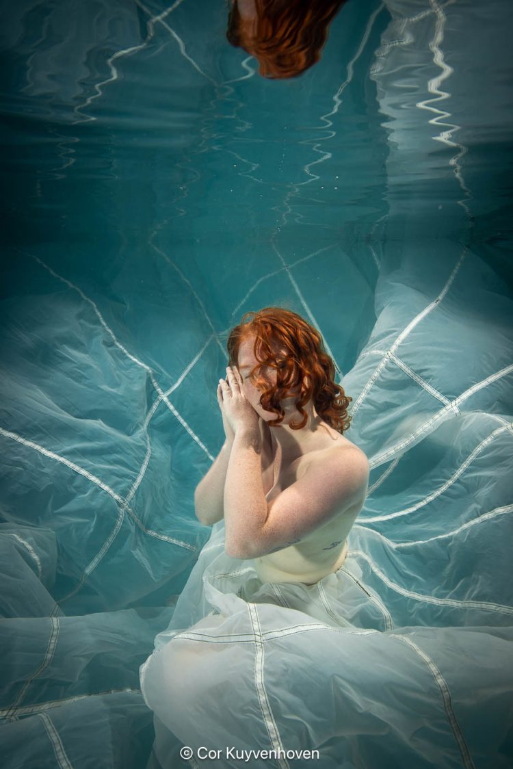 Dame onderwater met parachute in zwembad.