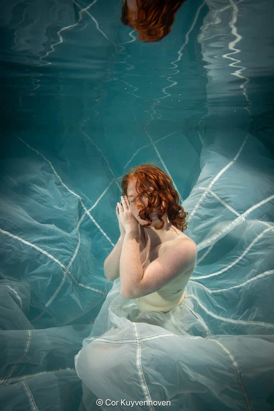 Dame onderwater met parachute in zwembad.