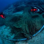 Alt tekst: Onderwaterfotografie van twee duikers die een verloren visnet aan het duiken zijn op de zeebodem.
