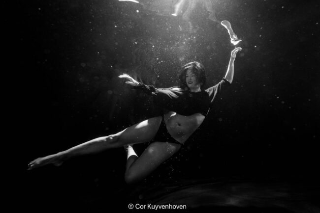 Een prachtige artistieke zwart-wit onderwaterfoto van Noi Pakon in beweging, met creatieve belichting en waterbubbels, perfect voor kunst- en fotografie doelen.