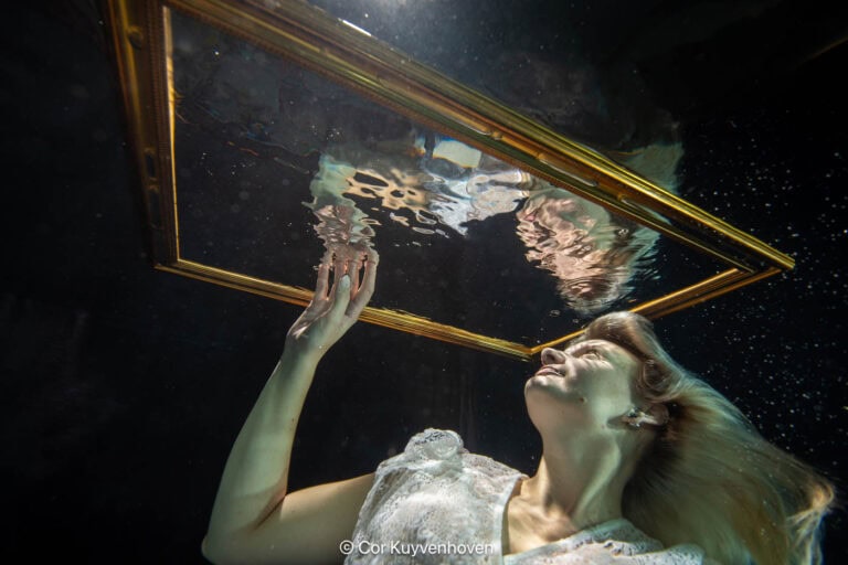 Creatieve onderwaterfotografie voor marketingcampagnes Een vrouw onderwater met spiegel en gouden lijst, symboliseert creativiteit en kunstzinnigheid, vastgelegd door Cor Kuyvenhoven voor inspirerende kunst- en lifestylebeelden.