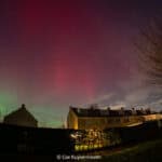 Noorderlicht boven een huis in de nacht.