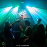 Gladde paling met feestvierders onder kleurrijke lichten en DJ achter de draaitafel.