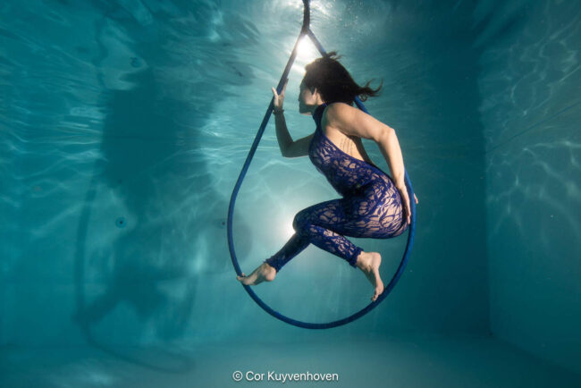 Onderwaterfoto van een vrouw. Noi Pakon die in een zwemcirkel zweeft, met helder water en zonlicht dat door het water schijnt. Perfect voor sport- en zwemgerelateerde content.